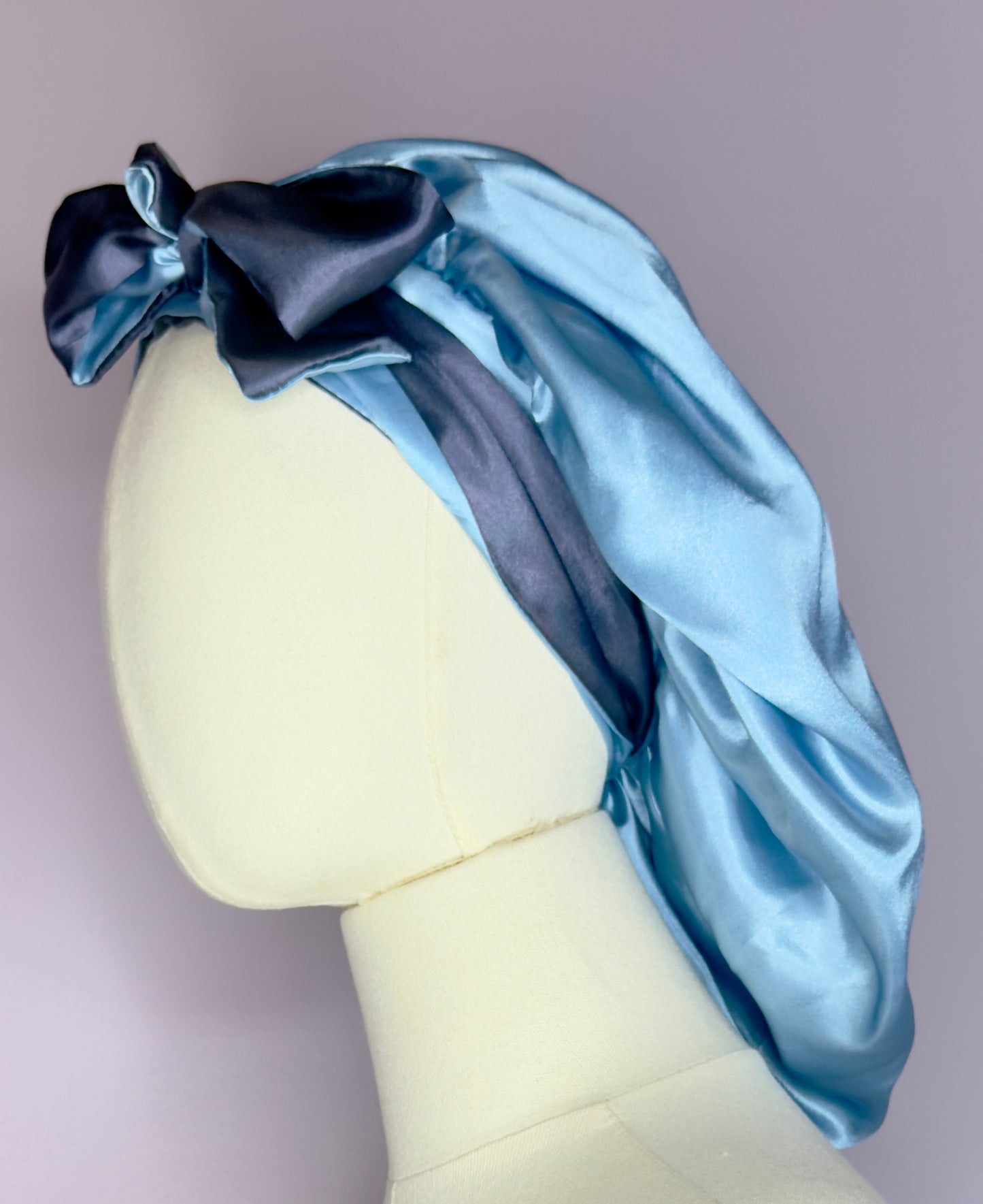 Double layer reversible satin hair bonnet with long ties to adjust comfort in light blue and dark blue colors. 