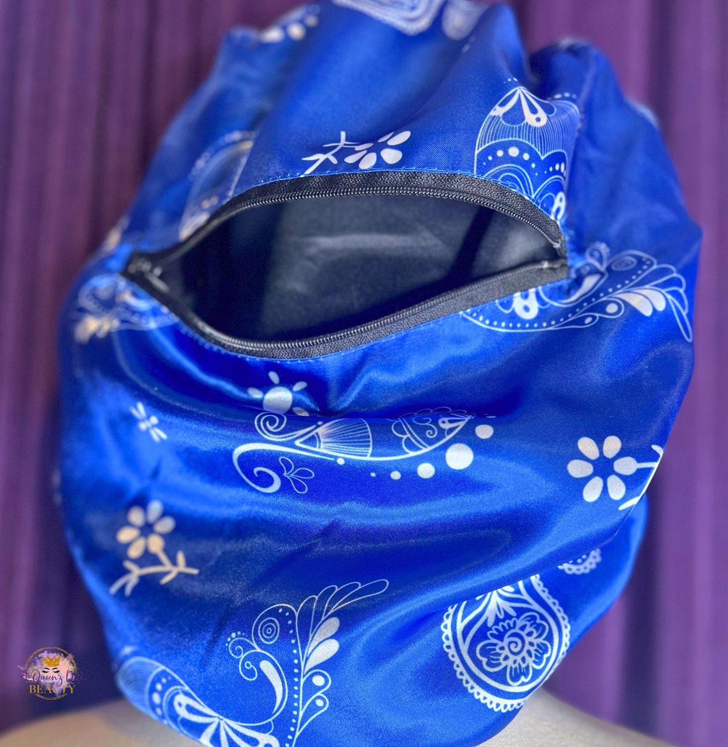 AQueenzDen blue satin hair bonnet with white paisley pattern and a functional zipper pocket.