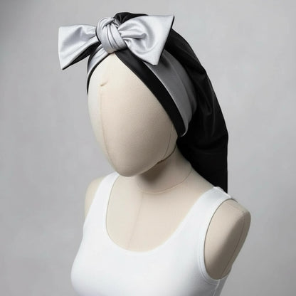 AQueenzDen black and silver double layer satin bonnet with adjustable ties and a large bow detail.