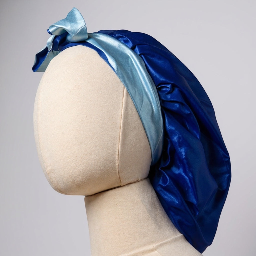 AQueenzDen double layer reversible satin bonnet in royal blue with light blue adjustable ties tied in a bow.