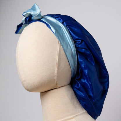 AQueenzDen double layer reversible satin bonnet in royal blue with light blue adjustable ties tied in a bow.