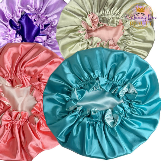 A Queenz Den adjustable double layer reversible satin hair bonnet in purple, mint green, coral, and teal.