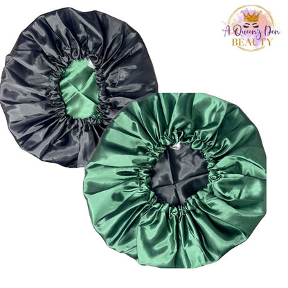 A Queenz Den reversible satin bonnet in black and emerald green. Features adjustable tie and double layer protection for natural hair.