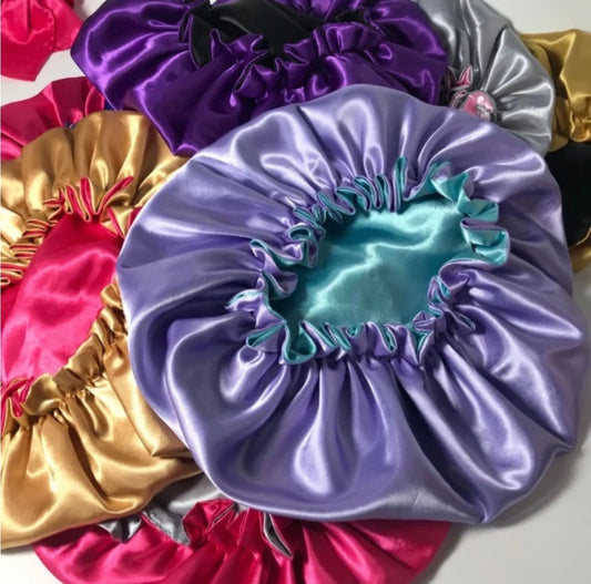 AQueenzDen satin bonnets in various vibrant colors like purple, pink, gold, and teal, featuring a silky sheen and ruffled edges.