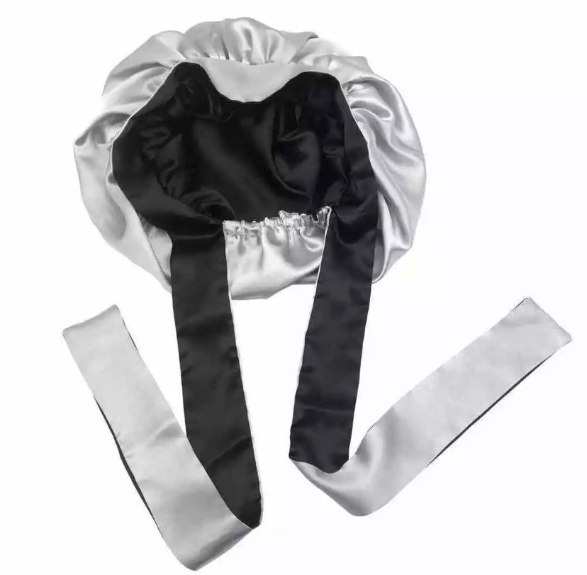 Double layer reversible satin hair bonnet with long ties to adjust comfort in black and silver colors. 